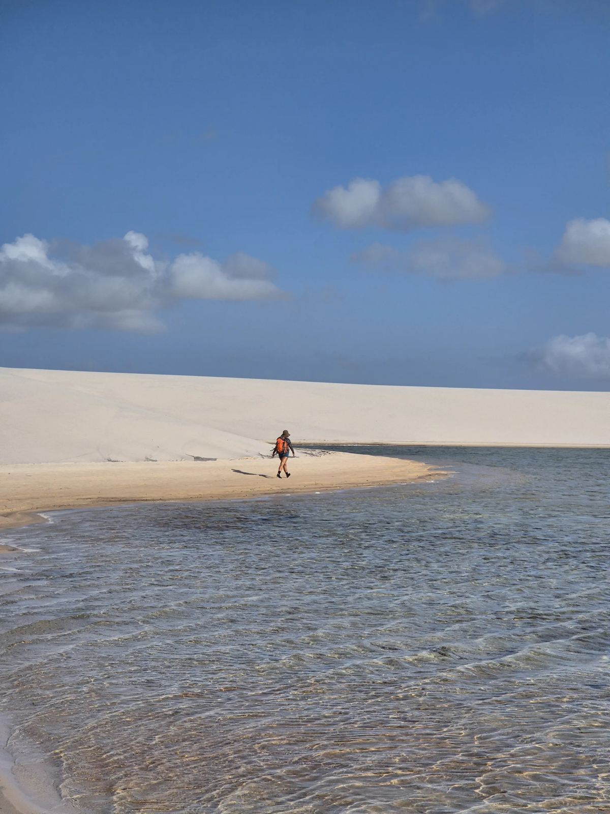 Guia caminhando às margens de uma lagoa nos Lençóis Maranhenses